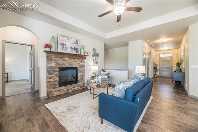 5126 Pring Ranch Road Colorado Springs, CO 80922 - Photo 10 of 32 Living room featuring a tray ceiling, and large gas fireplace framed with stone.