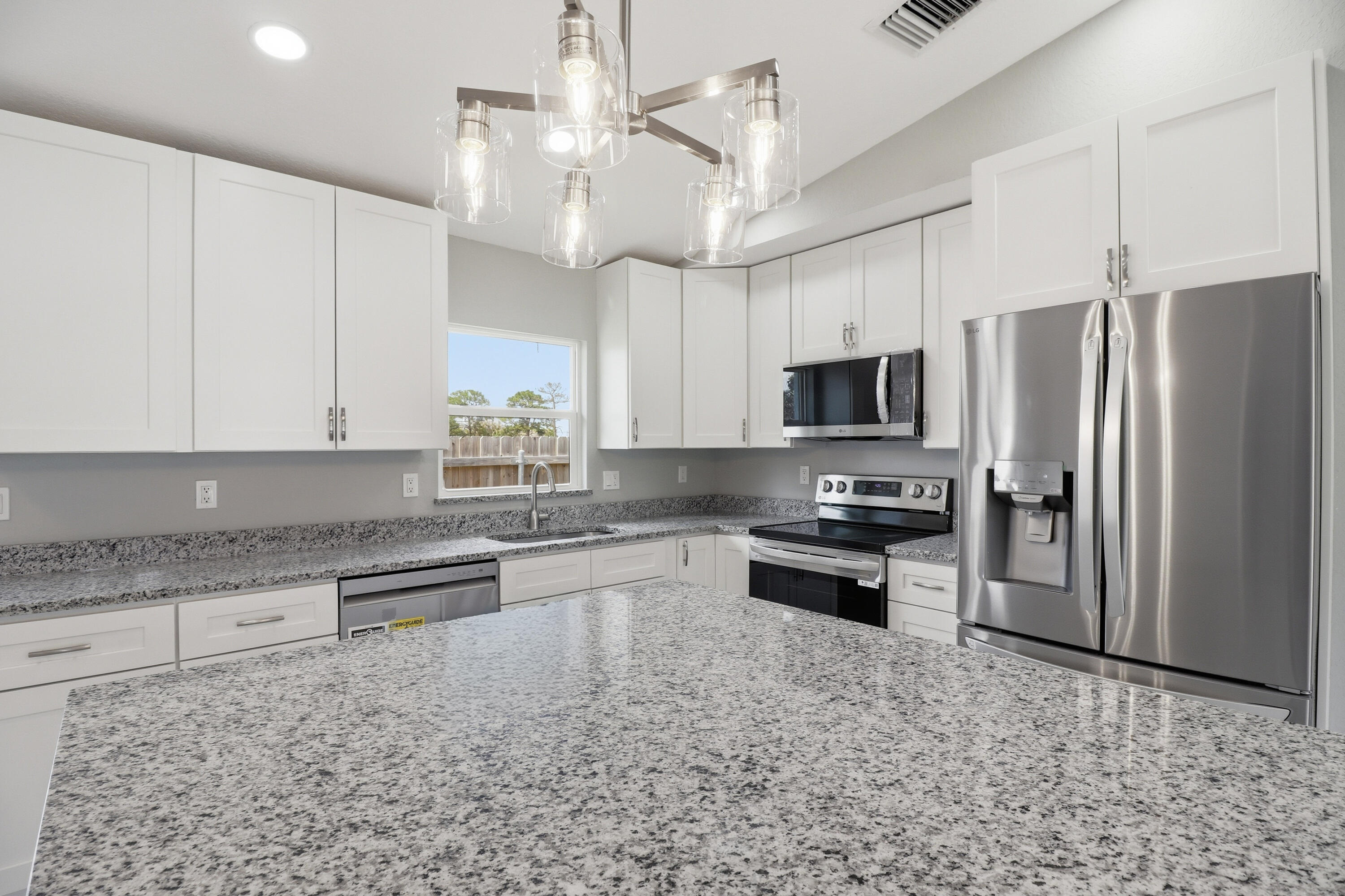 2805 Southeast Carroll Street Stuart, FL 34997 - Photo 6 of 21 a kitchen with granite countertop a refrigerator a sink a stove a microwave a counter top space and cabinets