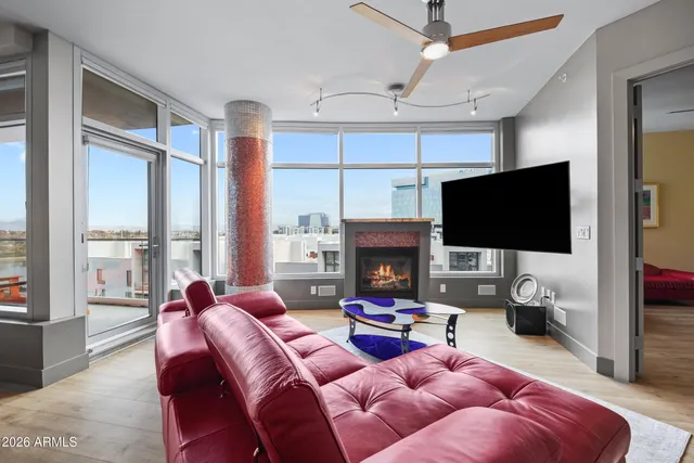 a living room with furniture a flat screen tv and a floor to ceiling window