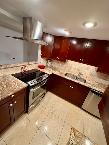 a large kitchen with stainless steel appliances granite countertop a sink and wooden cabinets