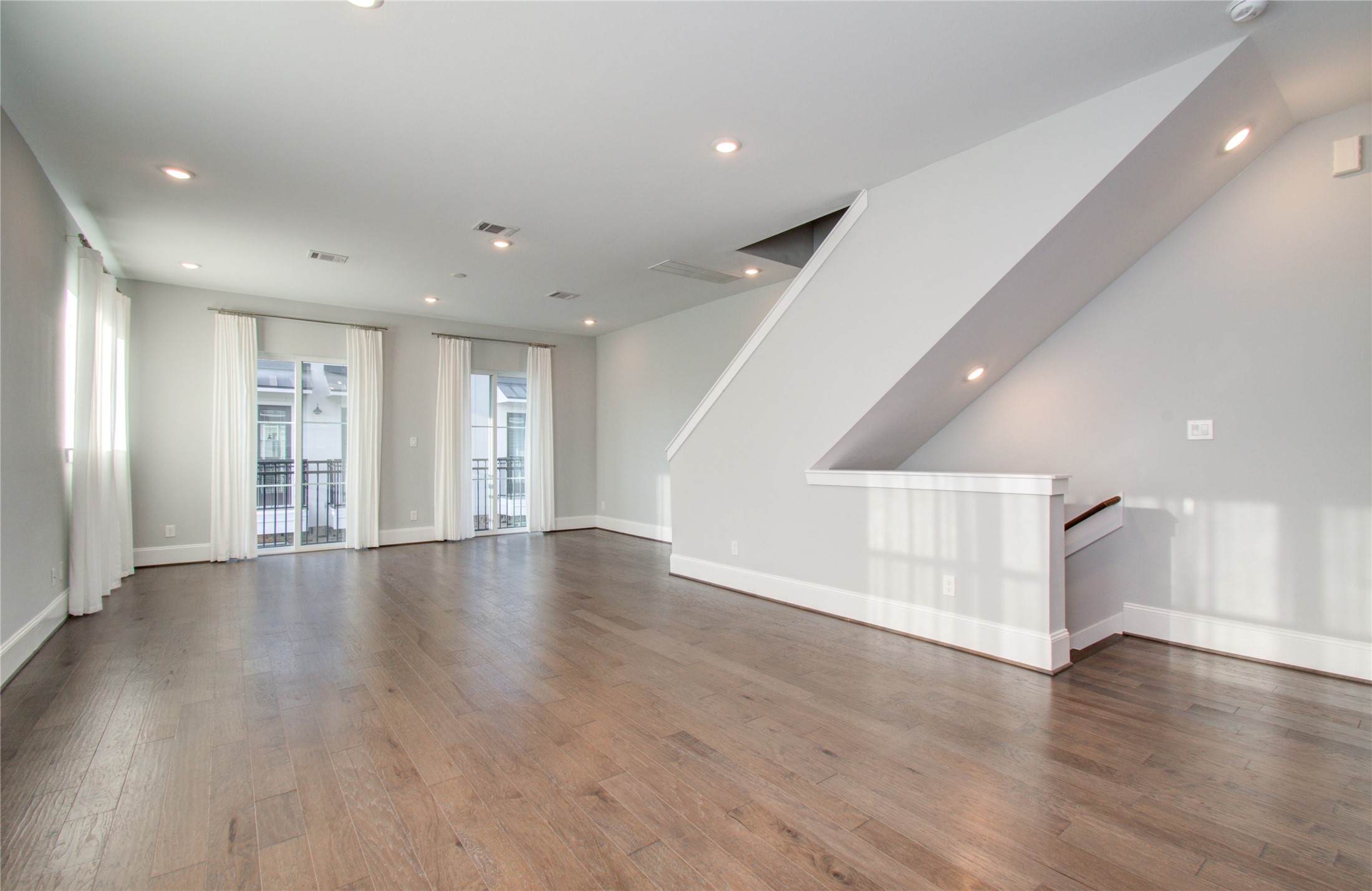1262 North Post Oak Road, Unit A Houston, TX 77055 - Photo 28 of 50 An alternative view of the open living hall emphasizes the modern architectural lines created by the staircase partition and clean baseboard trim along the neutral gray walls.