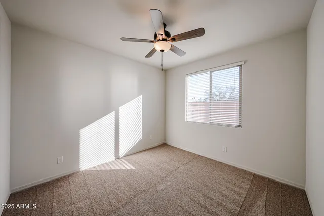 an empty room with windows and ceiling fan