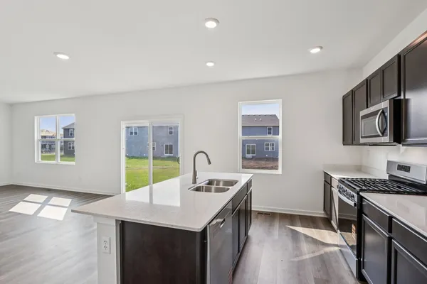 a kitchen with stainless steel appliances a sink a stove a microwave a refrigerator a counter top space and cabinets