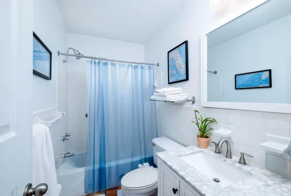a work room with stainless steel appliances a window wooden floor and a ceiling fan