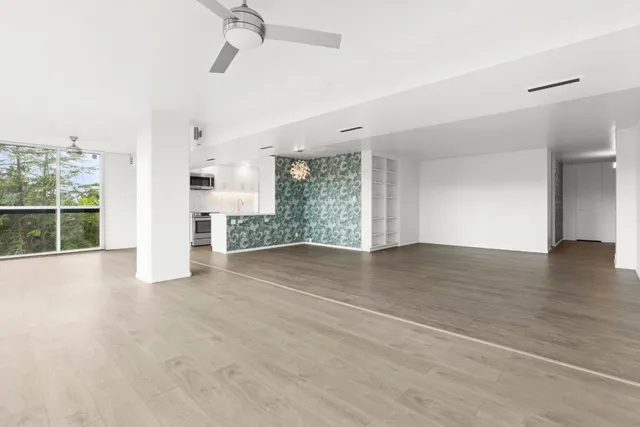 a view of empty room with wooden floor and fan