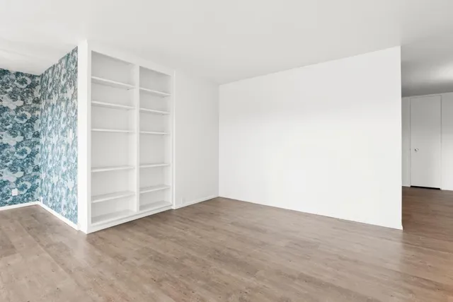 a view of an empty room with wooden floor and closet