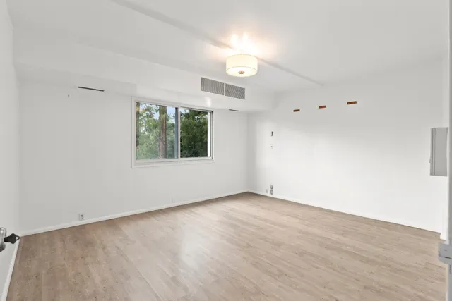 an empty room with wooden floor and windows