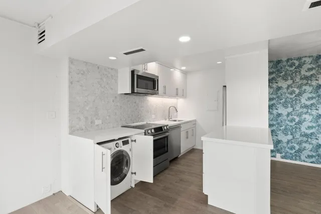a kitchen with a sink a stove top oven and white cabinets