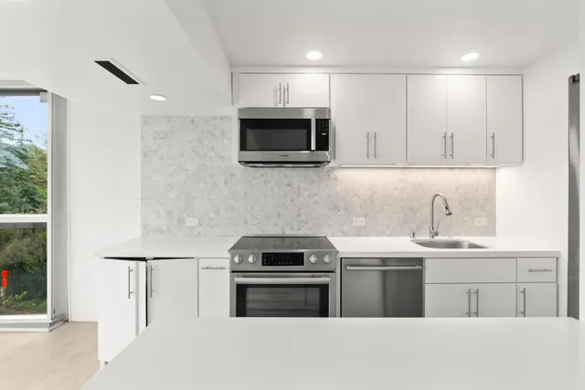 a kitchen with stainless steel appliances a sink stove and microwave