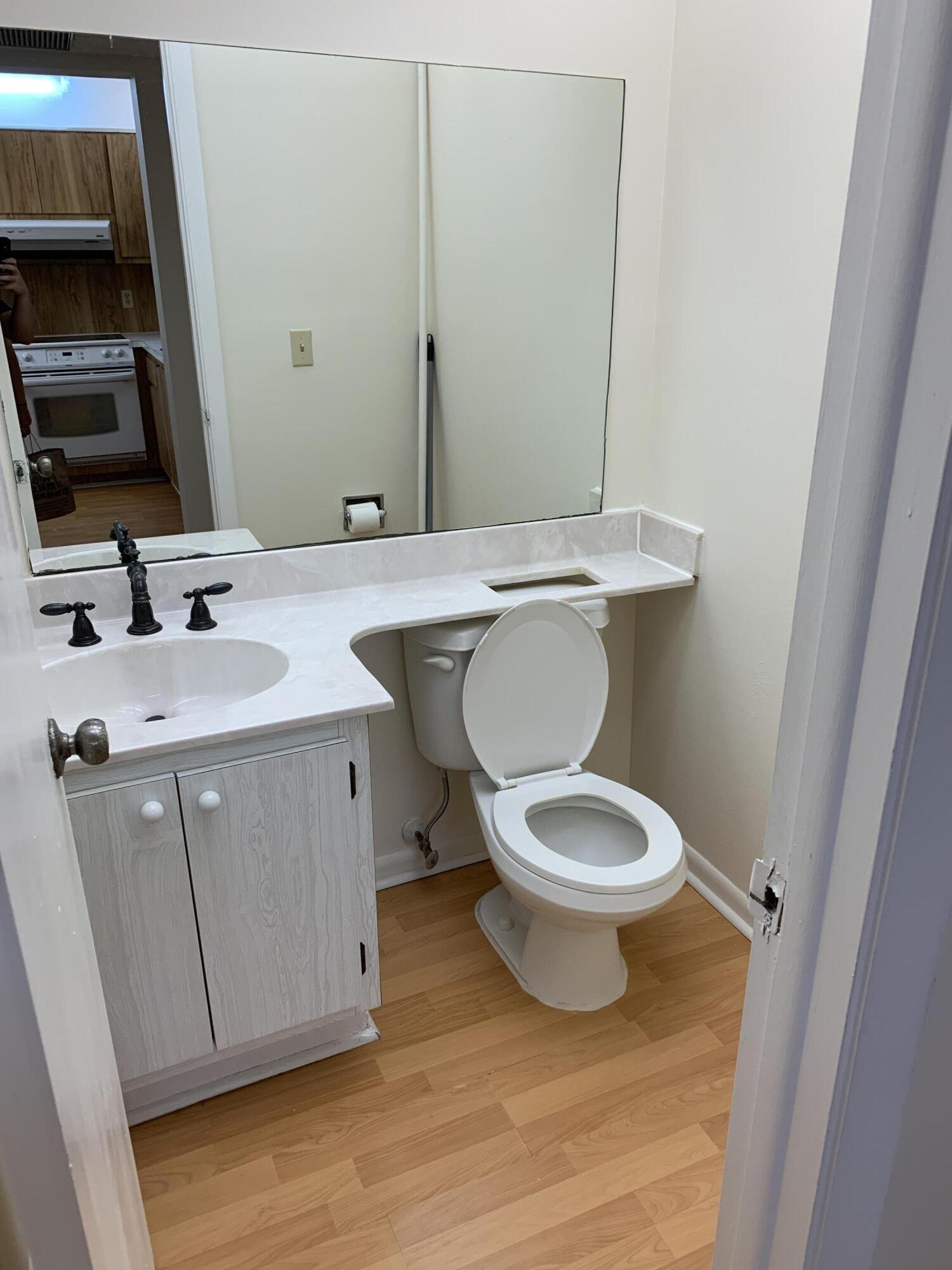 9273 Southwest 8th Street, Unit 416 Boca Raton, FL 33428 - Photo 12 of 14 a bathroom with a toilet a sink and mirror