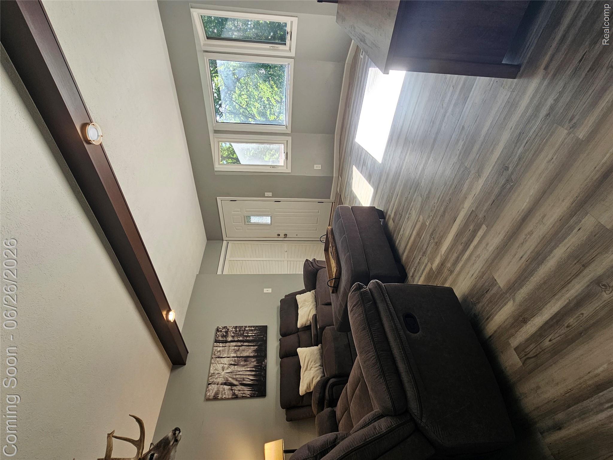 11211 Boyce Road Chelsea, MI 48118 - Photo 5 of 22 Living area featuring wood-finish flooring, exposed ceiling beams with recessed lighting, a white entry door with a decorative glass insert, and a bay window configuration