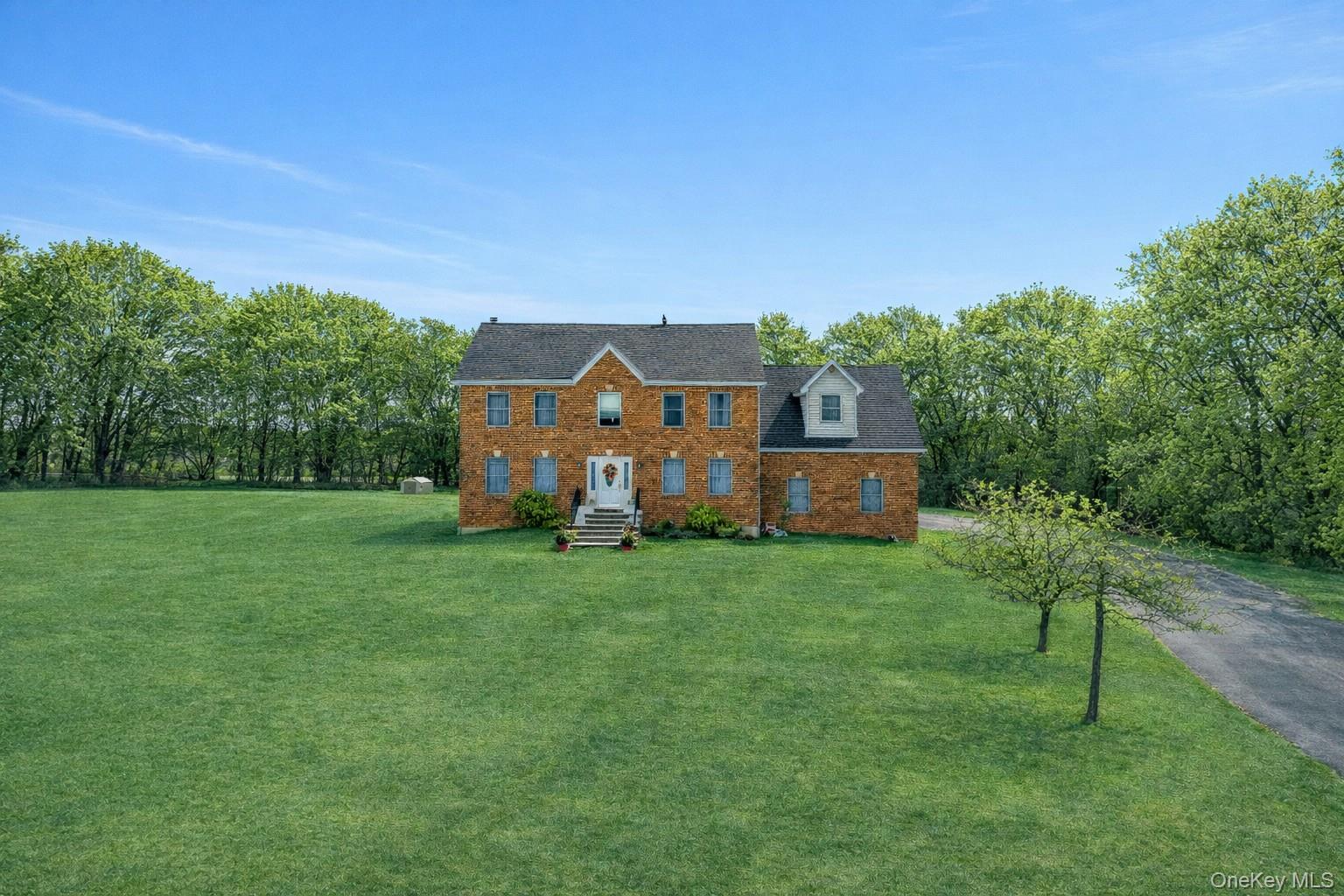 7 Angela's Way Goshen, NY 10924 - Photo 37 of 45 View of front facade featuring a front lawn, view of scattered trees, and brick siding