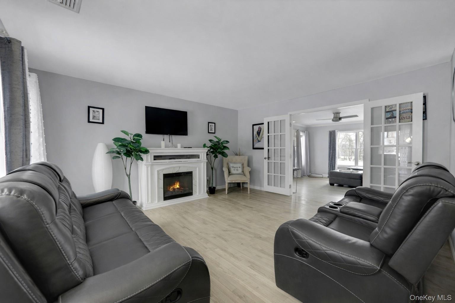 7 Angela's Way Goshen, NY 10924 - Photo 5 of 45 Living area featuring light wood-style flooring, a lit fireplace, a ceiling fan, and french doors