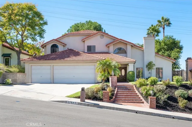 a front view of a house with a yard and potted plants