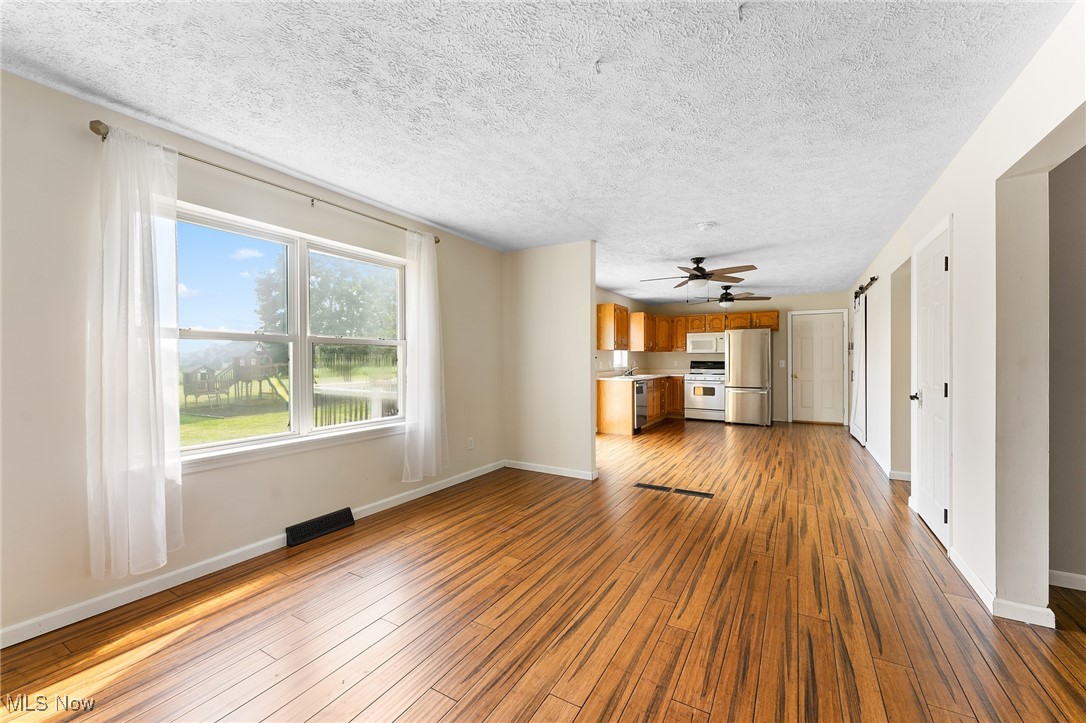 6272 Merwin Chase Road Brookfield, OH 44403 - Photo 6 of 38 Unfurnished living room featuring ceiling fan, wood-type flooring, and a textured ceiling