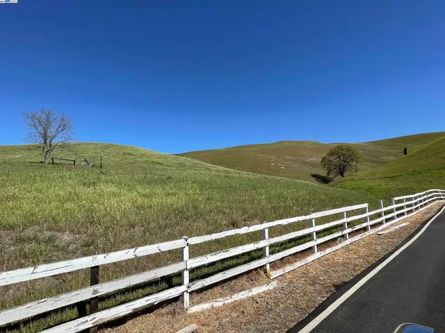a view of a green field with wooden fence