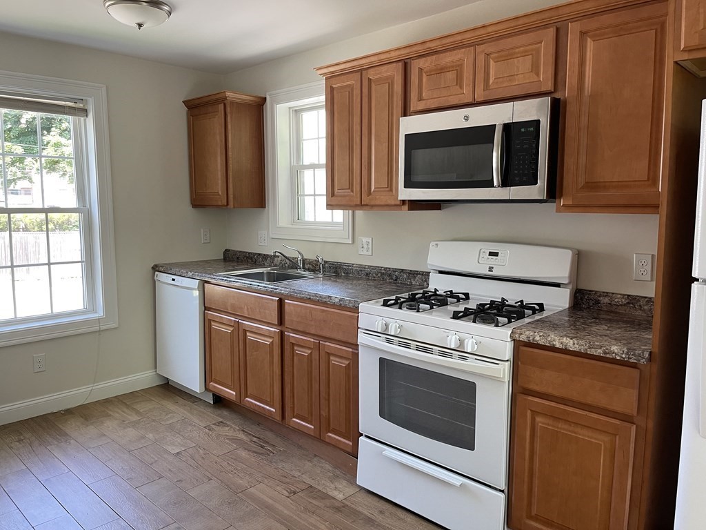26 Main Street, Unit REAR Framingham, MA 01702 - Photo 2 of 11 a kitchen with stainless steel appliances granite countertop wooden cabinets stove top oven and sink