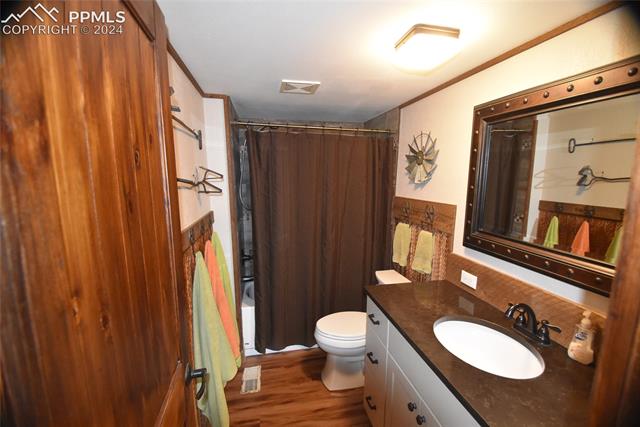 9990 Hahn Road Calhan, CO 80808 - Photo 7 of 25 Full bathroom featuring shower / bath combo, crown molding, wood-type flooring, toilet, and vanity