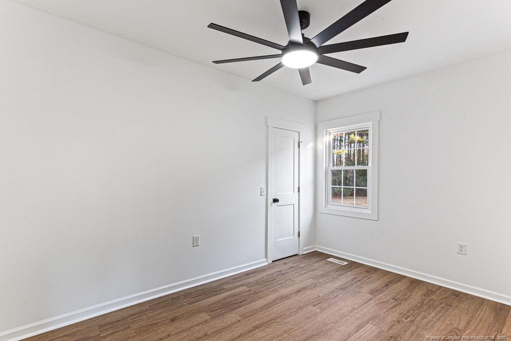 447 T T Johnson Road Carthage, NC 28327 - Photo 26 of 49 an empty room with wooden floor ceiling fan and windows