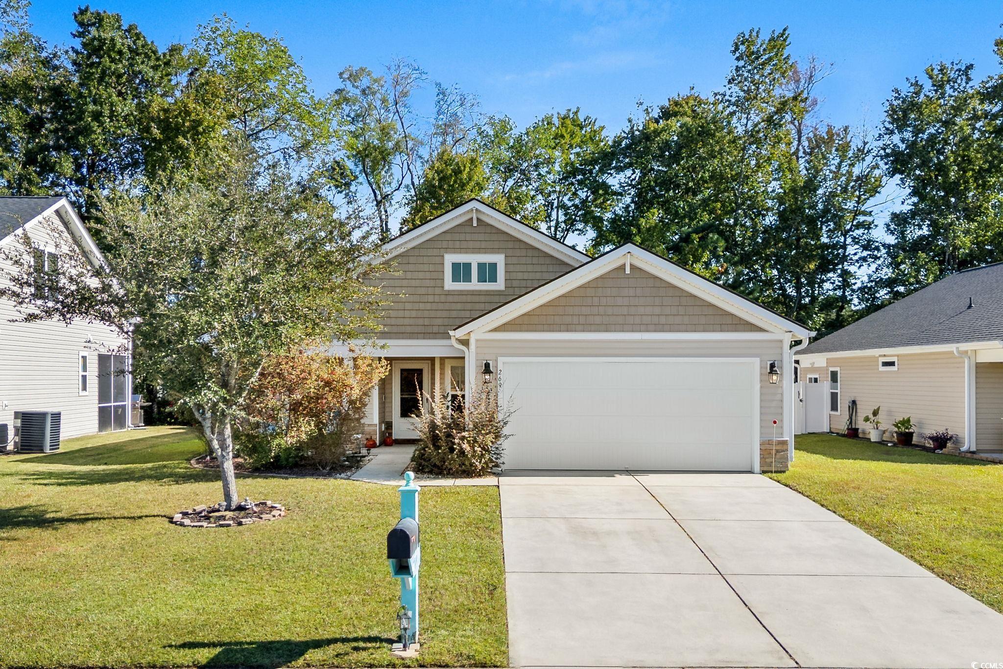 View of front of house with a front yard, concrete driveway, an attached garage, and stone siding