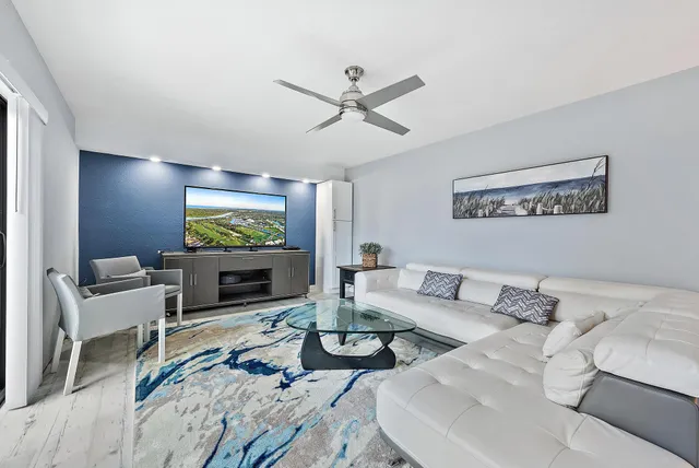 a living room with furniture a flat screen tv and a large window