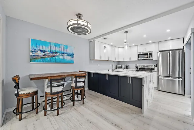 a kitchen with stainless steel appliances granite countertop a stove top oven a refrigerator a sink and a dining table with wooden floor