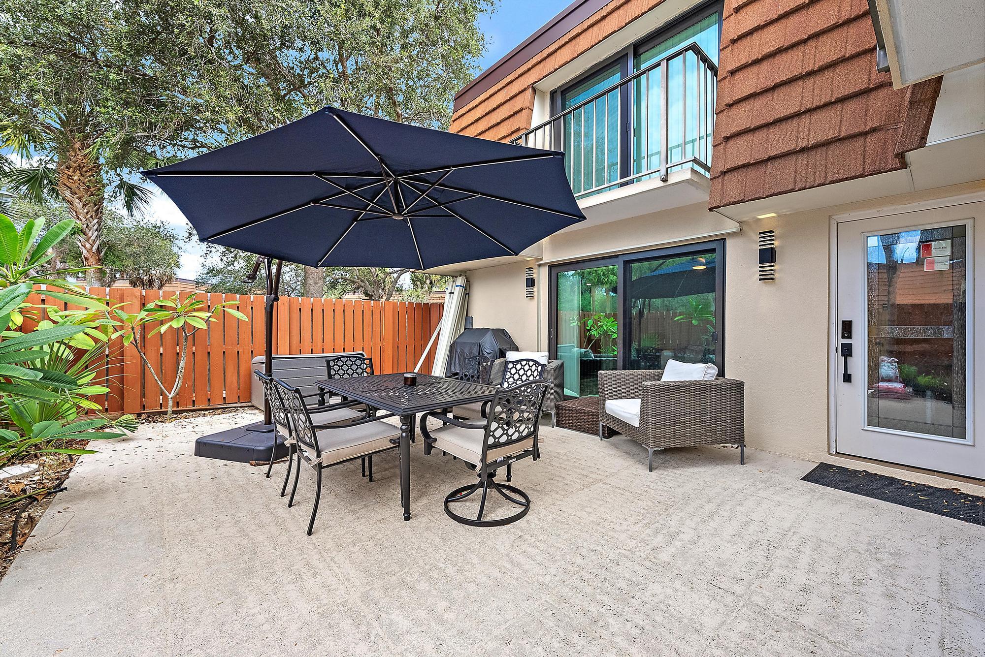 2902 29th Court Jupiter, FL 33477 - Photo 8 of 24 a view of patio with chairs and table under an umbrella