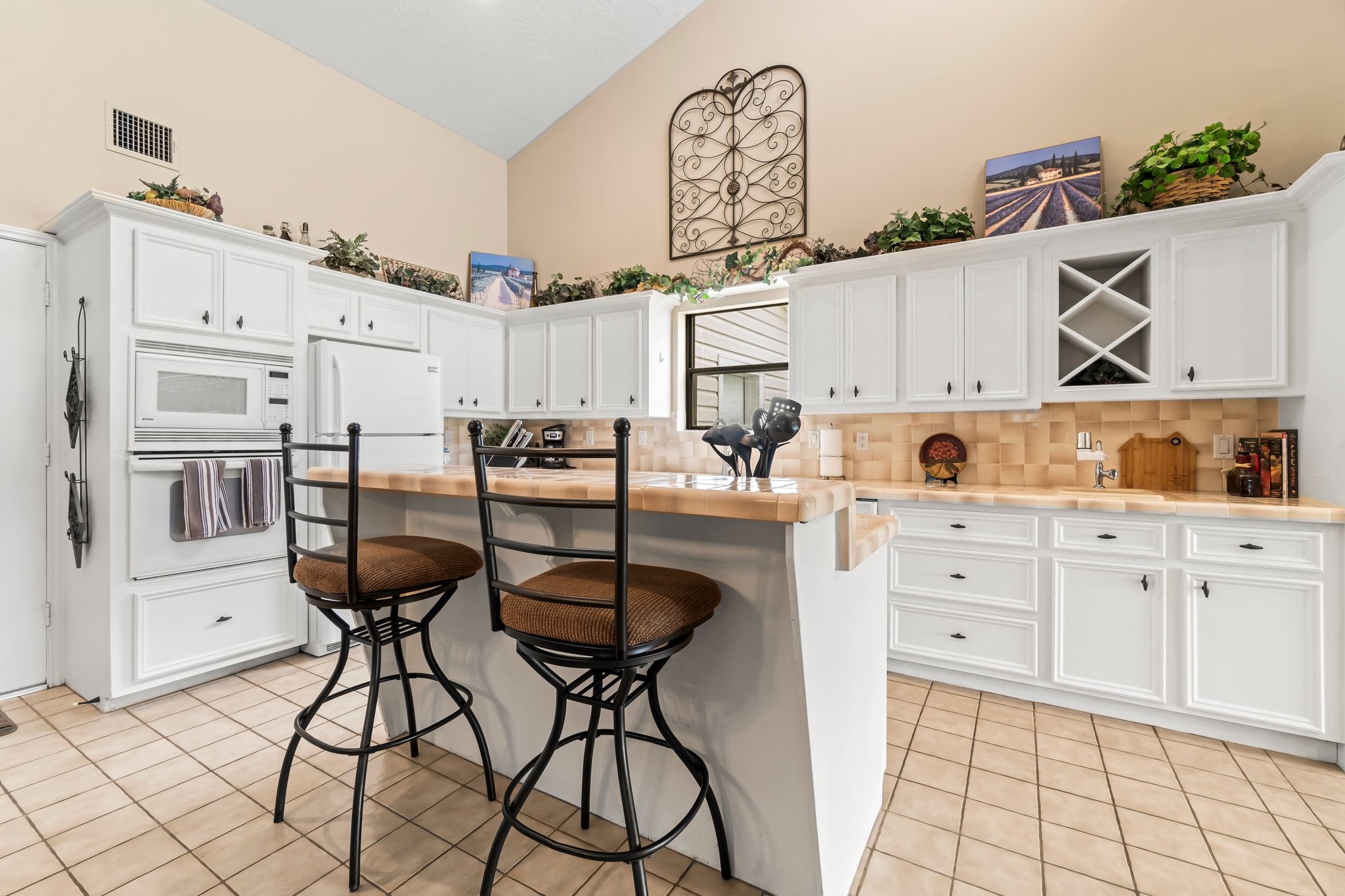 2839 Hemingway Drive Montgomery, TX 77356 - Photo 12 of 49 Bright, spacious kitchen with vaulted ceilings, featuring white cabinetry, a tiled backsplash, and a breakfast bar with seating. Equipped with modern appliances and decorative accents for a cozy, inviting atmosphere.