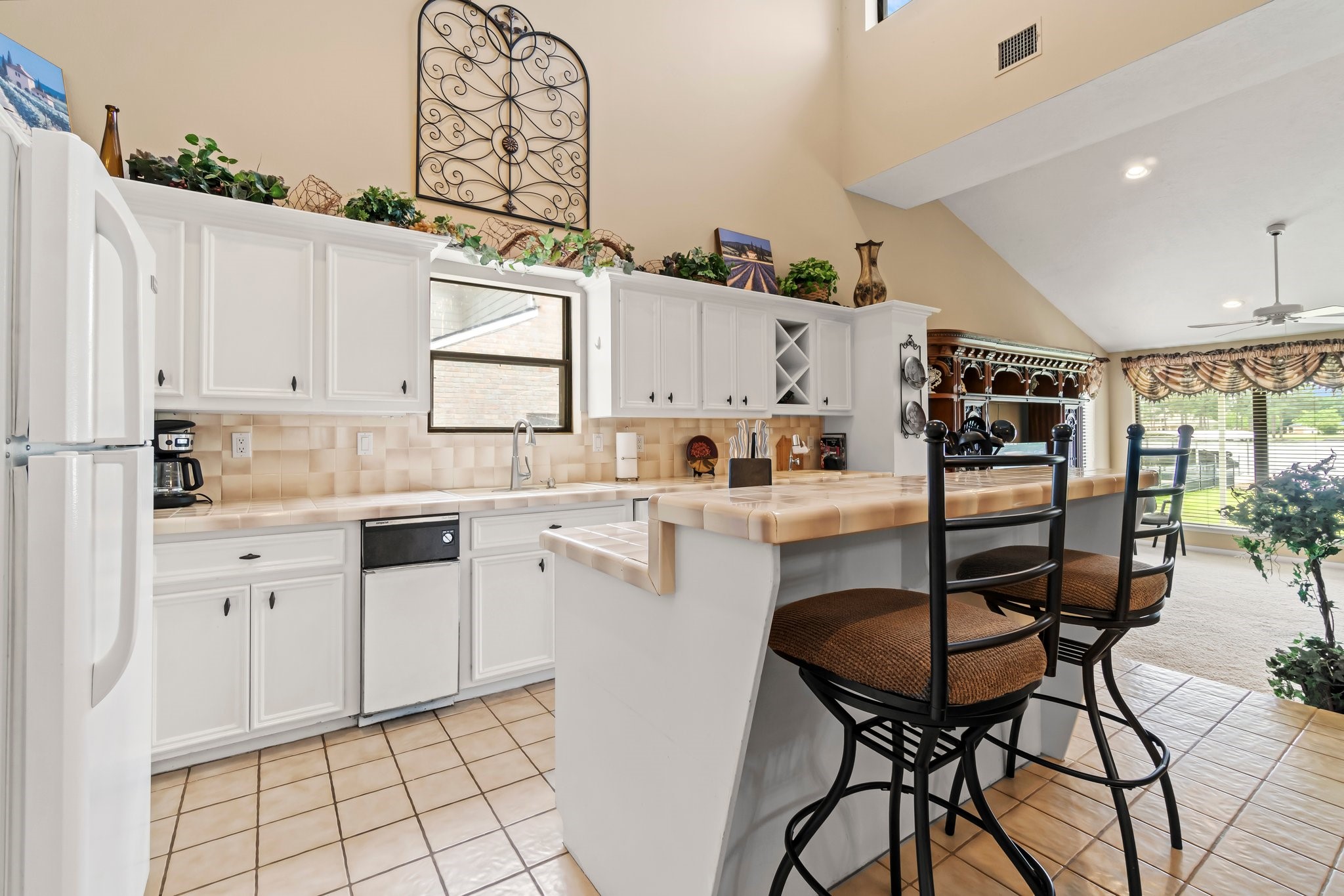 2839 Hemingway Drive Montgomery, TX 77356 - Photo 13 of 49 This inviting kitchen features white cabinetry, a breakfast bar with seating, and plenty of natural light. It opens into a spacious living area with large windows, creating a bright, airy atmosphere perfect for entertaining or family gatherings.