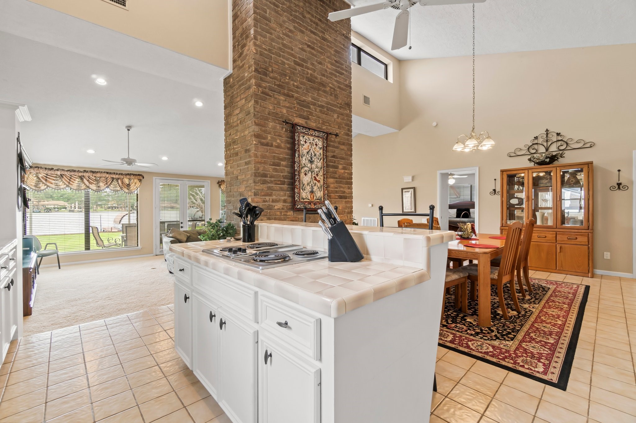 2839 Hemingway Drive Montgomery, TX 77356 - Photo 14 of 49 This spacious living area features a bright, open layout with a high ceiling, a central brick accent wall, and an inviting dining space. Large windows offer plenty of natural light, and the kitchen includes a tiled countertop with a built-in stove.
