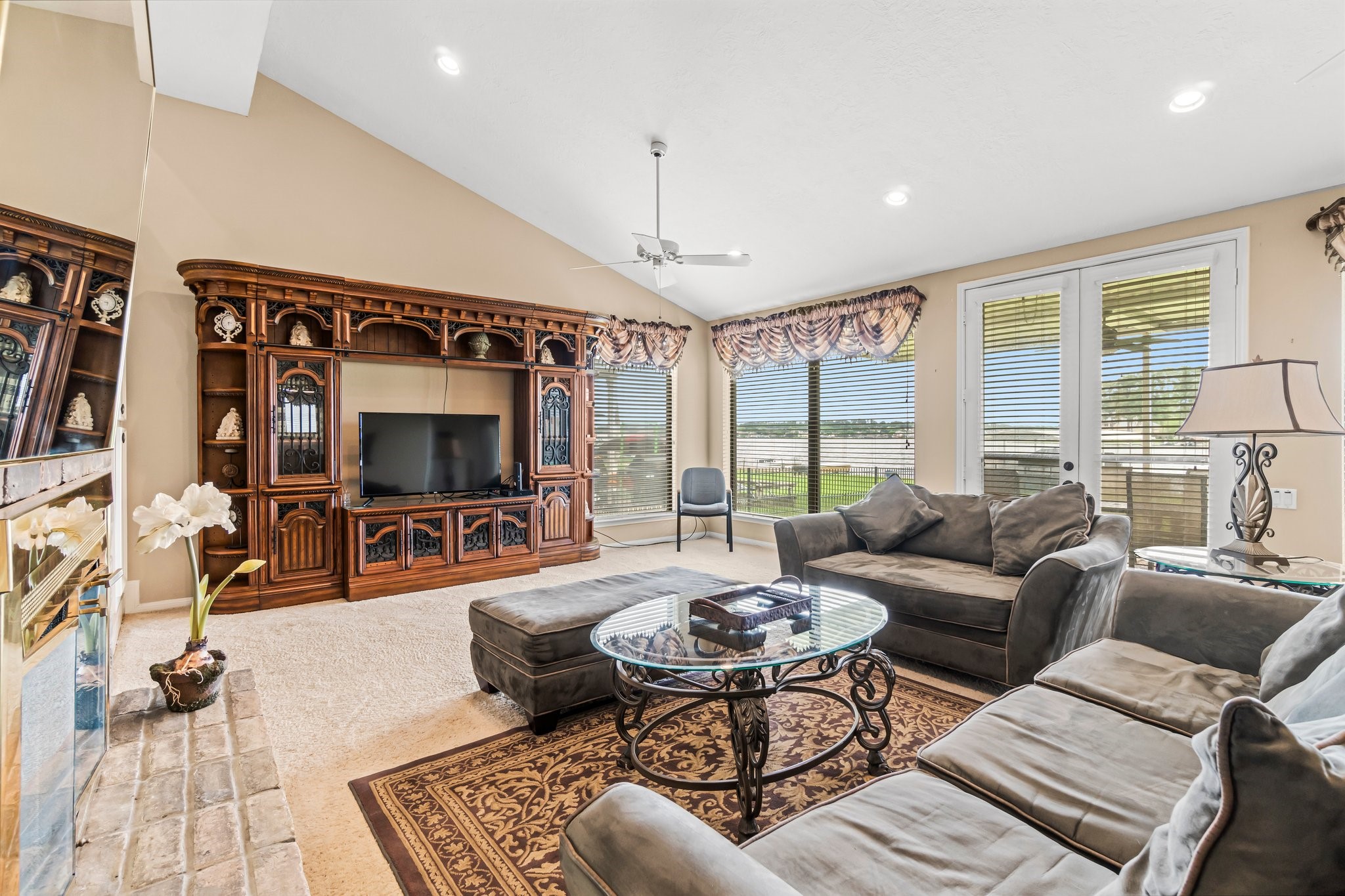 2839 Hemingway Drive Montgomery, TX 77356 - Photo 18 of 49 This inviting living room features a vaulted ceiling, elegant wood entertainment center, and plush sectional sofa. Large windows and glass doors offer abundant natural light and views of the backyard, creating a bright and airy atmosphere.