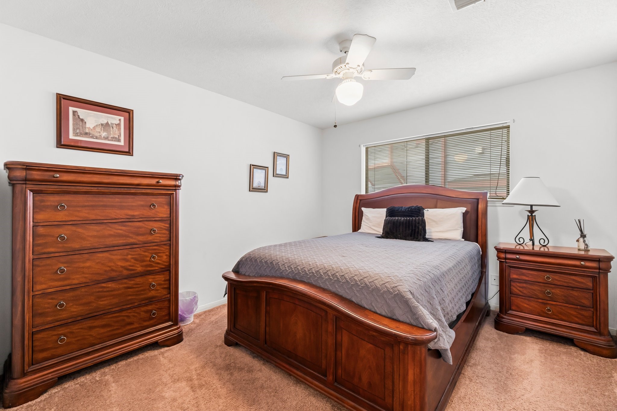 2839 Hemingway Drive Montgomery, TX 77356 - Photo 20 of 49 This bedroom features a cozy setup with a wooden bed frame, matching dresser, and nightstand. The room has carpeted flooring, a ceiling fan, and ample natural light from the window, creating a warm and inviting atmosphere.