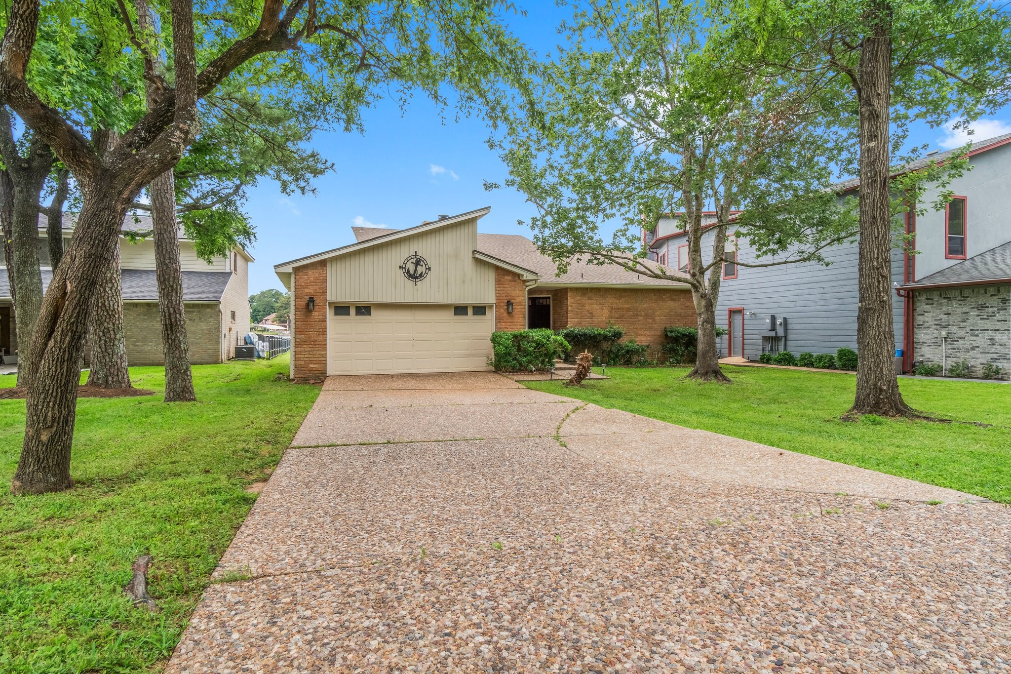2839 Hemingway Drive Montgomery, TX 77356 - Photo 2 of 49 Charming single-story home with a unique angled roof design. Features a spacious two-car garage and a long driveway. The front yard is landscaped with mature trees providing shade. The exterior is a blend of brick and siding, offering both durability and style.
