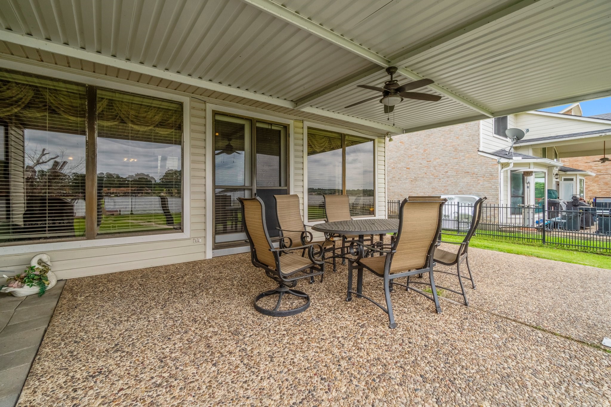 2839 Hemingway Drive Montgomery, TX 77356 - Photo 32 of 49 Spacious covered patio with ceiling fans and a seating area, featuring a textured stone floor. It overlooks a fenced yard, perfect for outdoor relaxation and entertaining.