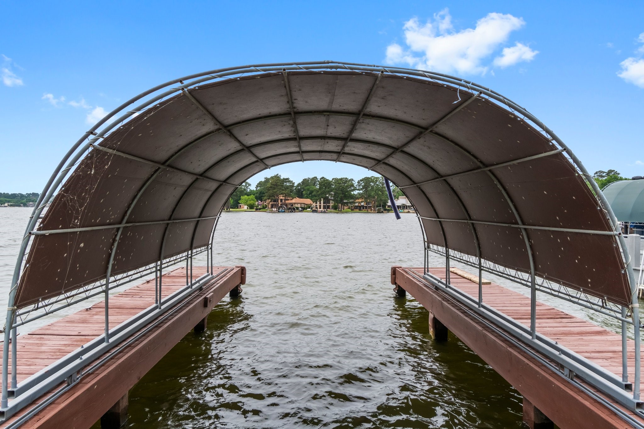 2839 Hemingway Drive Montgomery, TX 77356 - Photo 37 of 49 This photo features a covered boat dock with wooden walkways extending over a calm lake, offering scenic waterfront views and convenient lake access.