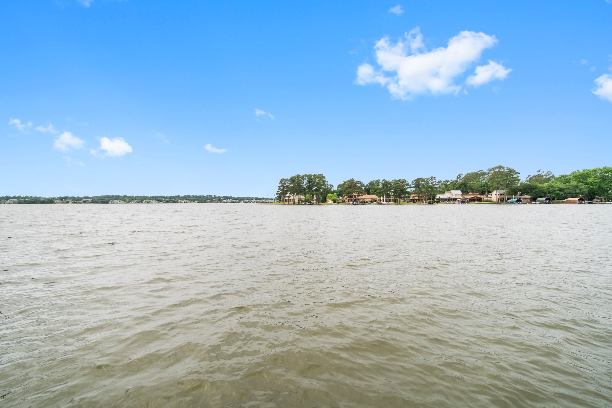 2839 Hemingway Drive Montgomery, TX 77356 - Photo 40 of 49 This photo showcases a serene waterfront view with expansive water and a distant shoreline lined with trees and homes, ideal for those seeking a peaceful lakeside living experience.