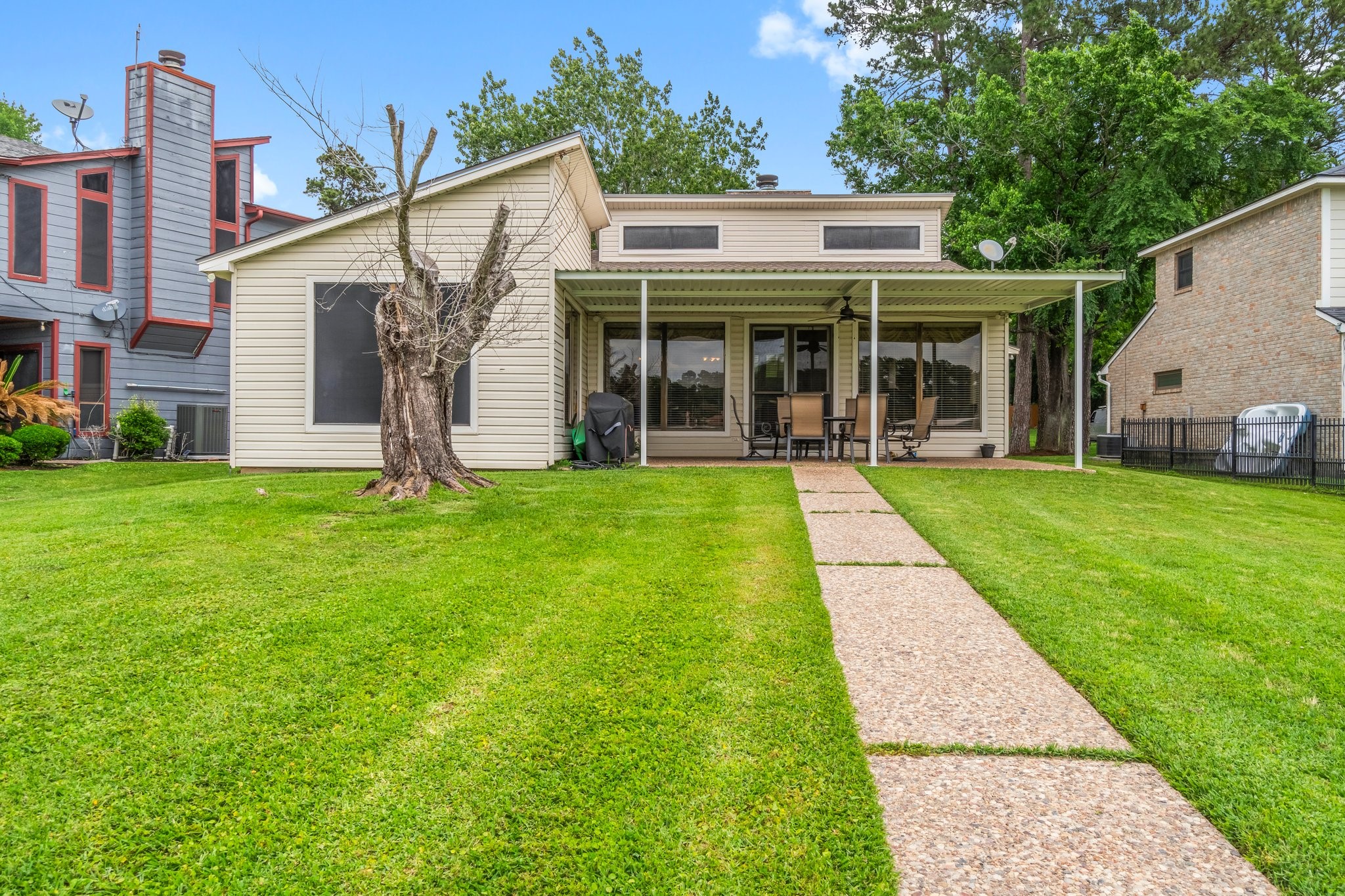 2839 Hemingway Drive Montgomery, TX 77356 - Photo 41 of 49 This charming home features a well-maintained lawn, a spacious covered patio perfect for outdoor gatherings, and large windows for ample natural light. The property offers a modern exterior with a paved walkway, nestled between two neighboring houses in a serene setting.