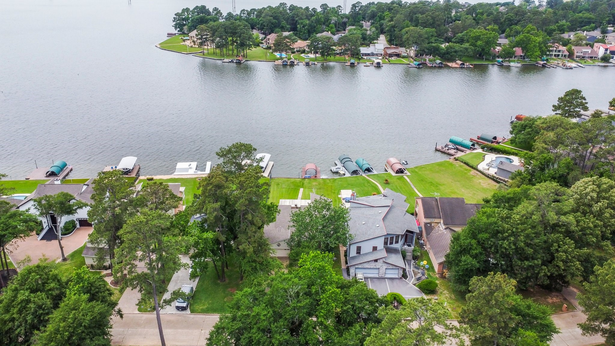 2839 Hemingway Drive Montgomery, TX 77356 - Photo 43 of 49 This photo showcases a lakefront property with direct water access, surrounded by lush greenery and neighboring homes. Ideal for those seeking a serene, picturesque setting with outdoor recreational opportunities.