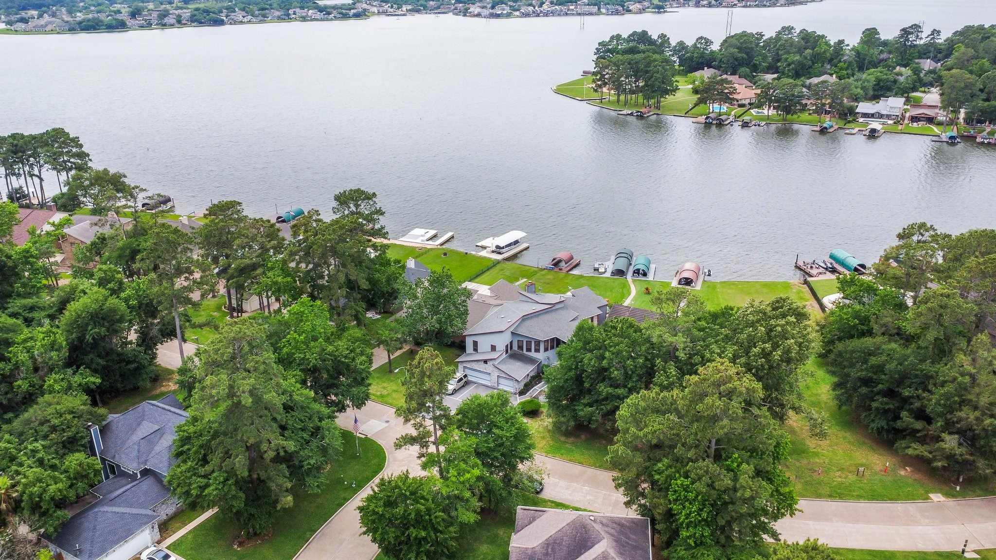 2839 Hemingway Drive Montgomery, TX 77356 - Photo 44 of 49 This aerial photo showcases a beautiful waterfront property with a spacious home surrounded by lush greenery. It features direct access to a serene lake, ideal for boating and scenic views. The neighborhood appears tranquil and well-maintained, offering a peaceful, nature-filled setting.