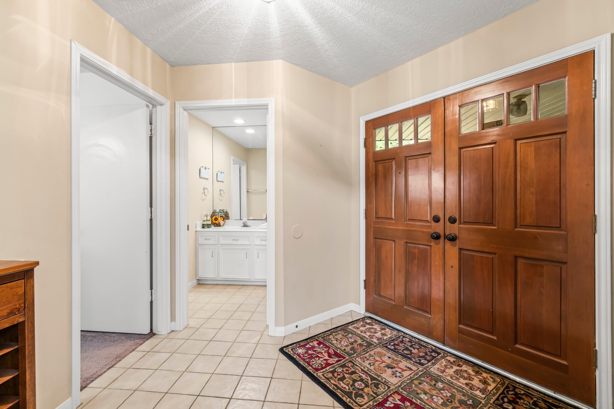2839 Hemingway Drive Montgomery, TX 77356 - Photo 6 of 49 This photo shows a welcoming entryway with warm wooden double doors and checkered tile flooring. It includes a view of an adjacent bathroom with a large mirror and white cabinetry, adding convenience and functionality.