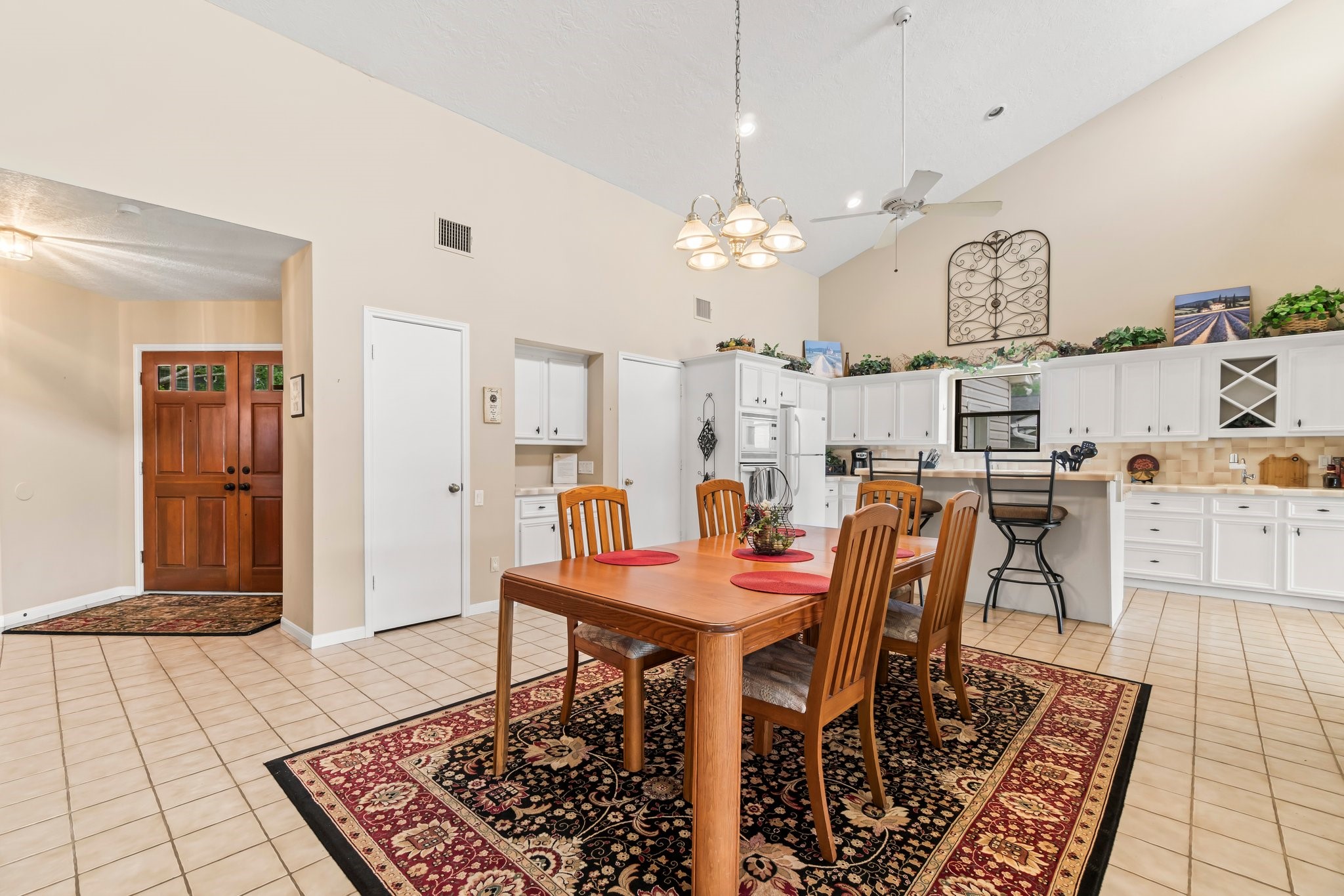 2839 Hemingway Drive Montgomery, TX 77356 - Photo 10 of 49 This spacious kitchen and dining area features high ceilings, abundant natural light, and a welcoming open layout. The kitchen boasts white cabinetry, ample counter space, and a breakfast bar. The dining area is accented by a warm wooden table set on a decorative rug, making it perfect for family gatherings.