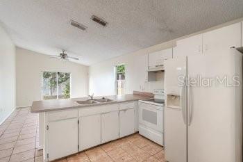 1032 Inkberry Court Orlando, FL 32811 - Photo 7 of 16 a kitchen with white cabinets and white appliances