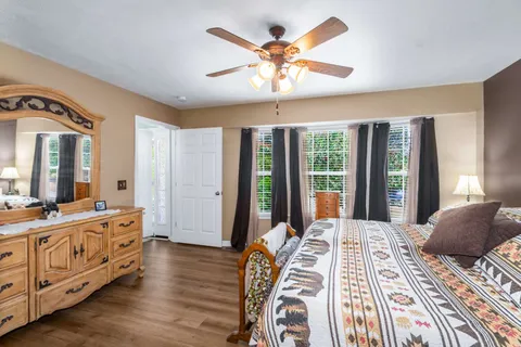 a bedroom with a bed a large window with wooden floor