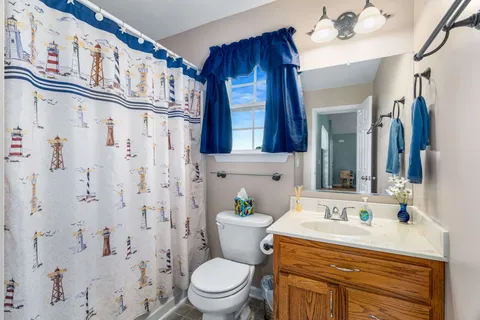 a bathroom with a granite countertop sink a toilet a mirror and shower curtain