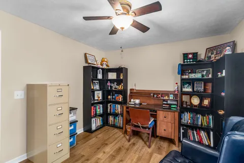 a view of a workspace with bookshelf and a window