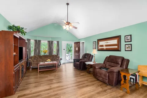 a living room with furniture a ceiling fan and a flat screen tv