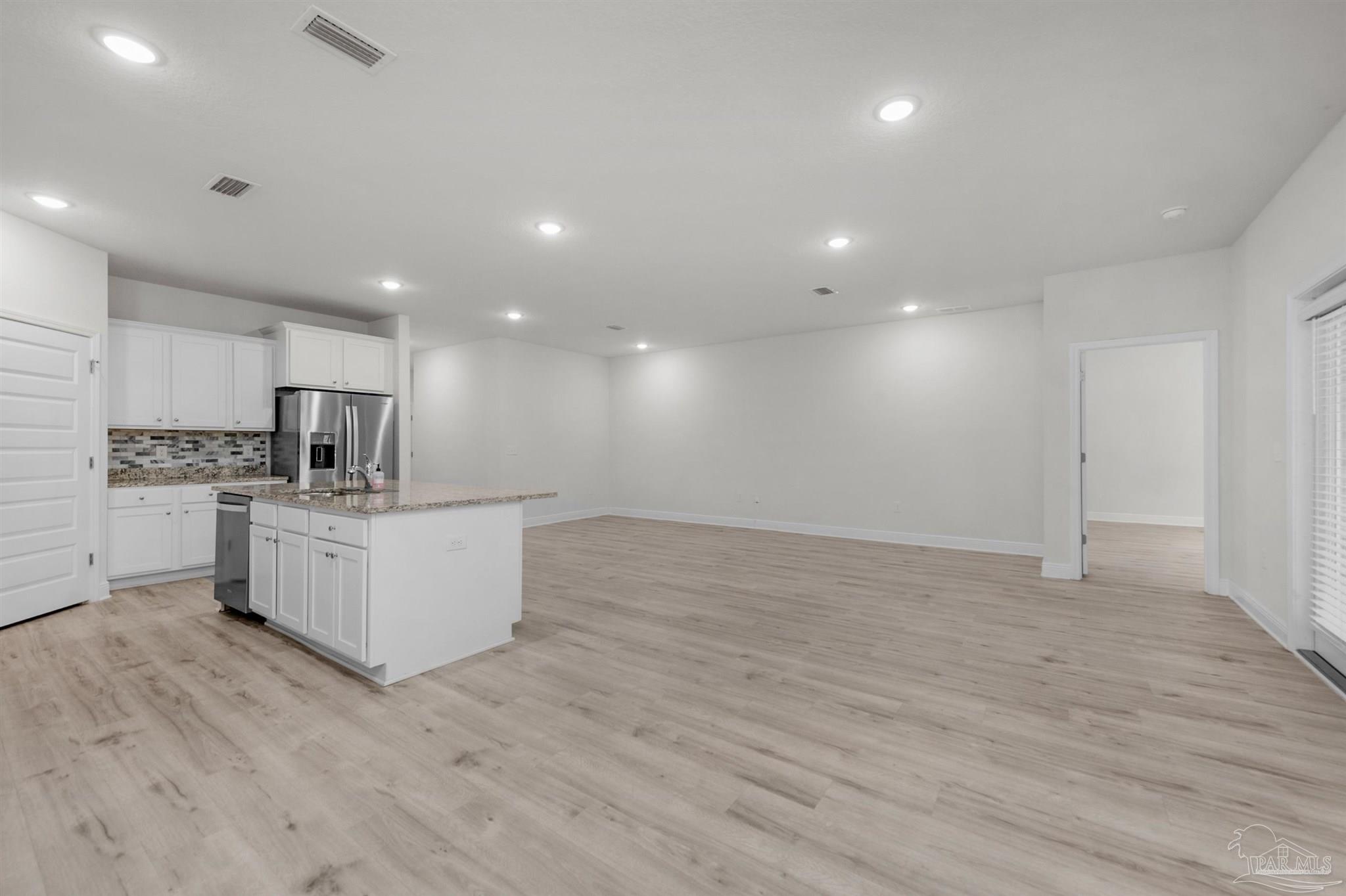 7814 Burnside Loop Pensacola, FL 32526 - Photo 20 of 41 a large white kitchen with kitchen island a sink dishwasher a oven and a large island with wooden floor