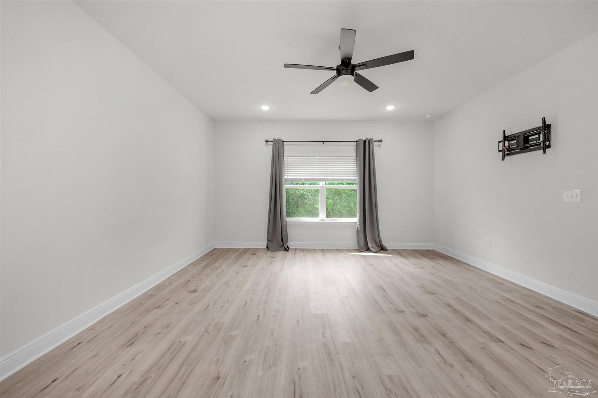 7814 Burnside Loop Pensacola, FL 32526 - Photo 29 of 41 an empty room with wooden floor a ceiling fan and windows
