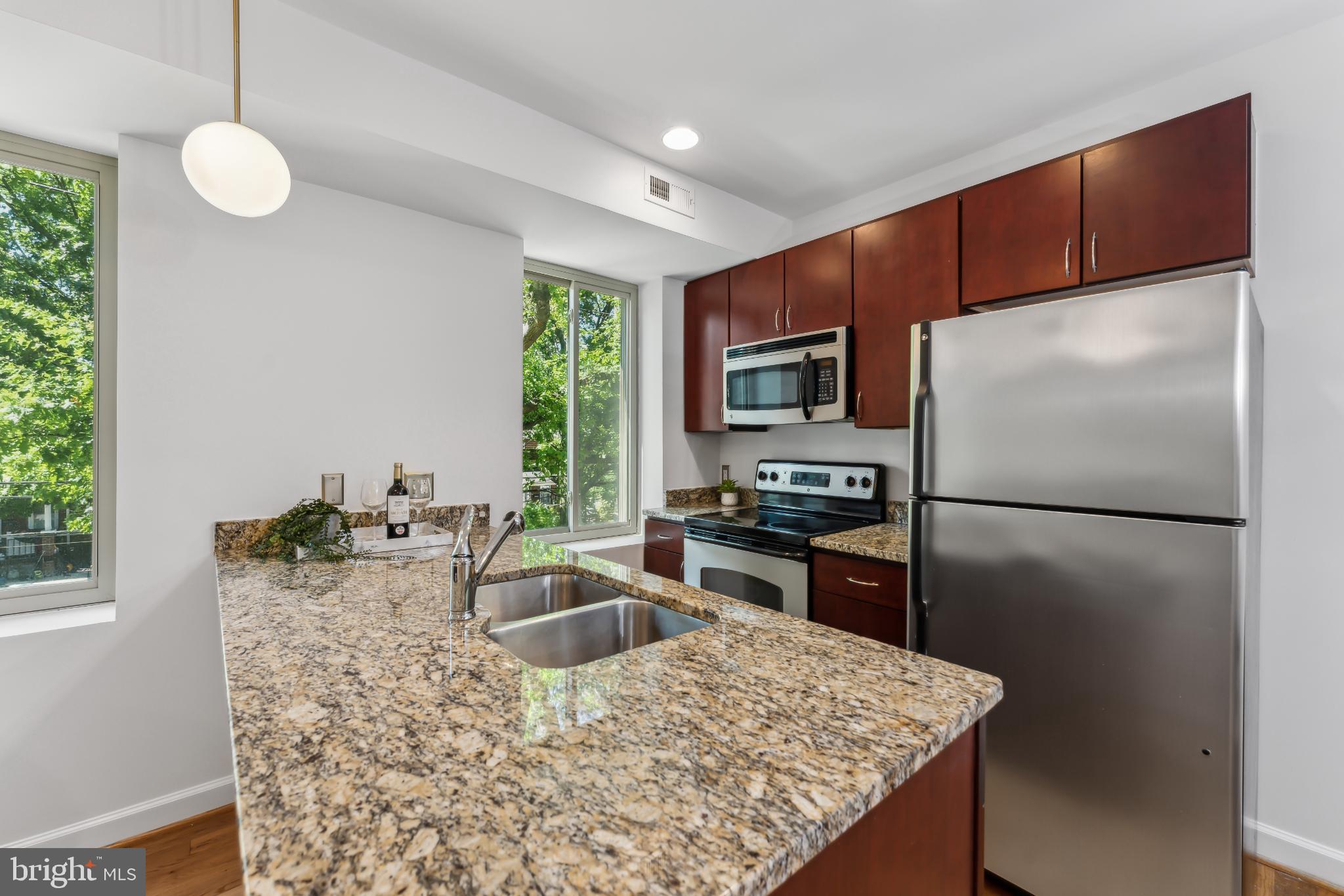 5403 9th Street Northwest, Unit 204 Washington, DC 20011 - Photo 3 of 19 a kitchen with kitchen island granite countertop a sink stove and refrigerator