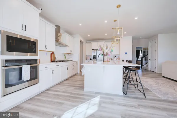 a large white kitchen with lots of counter space a sink appliances and cabinets